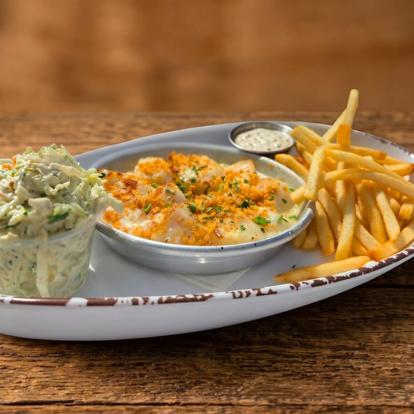 A white platter with baked scallops, french fries, coleslaw, and a side of tartar sauce.